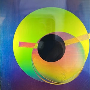 May include: Abstract art piece featuring overlapping circles in vibrant colors. A large, bright green circle dominates the composition, with a black circle at its center. Other circles display hues of yellow, orange, and purple, creating a dynamic visual effect.