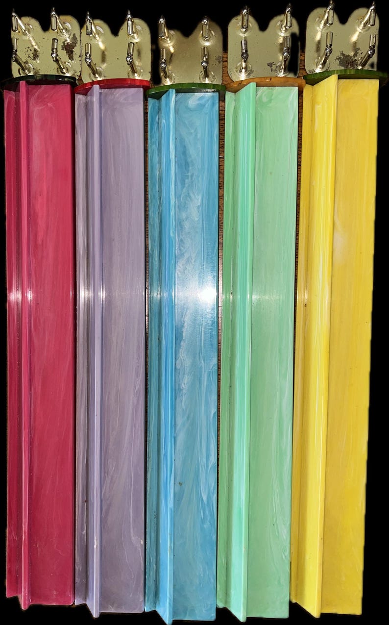 K&ouml;nnte beinhalten: Eine Sammlung farbenfroher Schrankgriffe im Vintage-Stil. Die Griffe sind in den Farbt&ouml;nen Rot, Lila, Blau, Gr&uuml;n und Gelb gehalten. Jeder Griff hat einen rechteckigen K&ouml;rper mit einer dekorativen Metalloberseite. Die Griffe sind wahrscheinlich aus einem haltbaren Kunststoffmaterial.