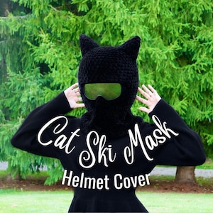 Puede incluir: Cubierta de casco de esquí de gato negro. La máscara tiene una textura negra peluda y un par de gafas negras. El texto "Cat Ski Mask Helmet Cover" está escrito en letras blancas en cursiva.