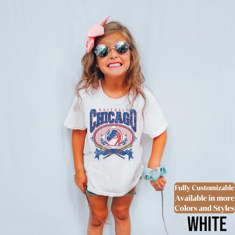 May include: White t-shirt with a vintage Chicago baseball design in blue and red. The shirt features the text "Baseball Chicago" above a baseball graphic with crossed bats. Additional text on the shirt reads "Fully Customizable Available in more Colors and Styles WHITE".