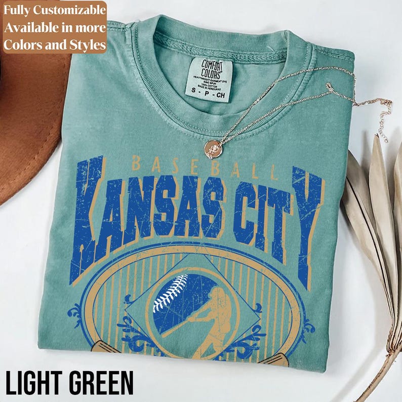May include: Light green t-shirt with a distressed blue and gold graphic that reads "Kansas City Baseball." The shirt features a baseball and batter illustration. The text "Fully Customizable Available in more Colors and Styles" is at the top, and "LIGHT GREEN" is at the bottom.