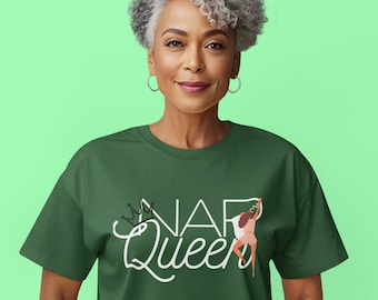 Op de afbeelding: Een groen T-shirt met witte tekst die "NAP Queen" zegt en een kroon boven het woord "NAP". Een cartoonvrouw houdt een deken boven haar hoofd, met de tekst "Zzz" erboven.
