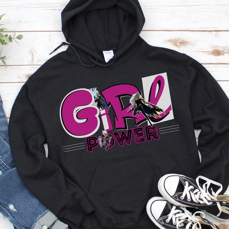 May include: Black hooded sweatshirt with the words "GIRL POWER" in a pink and white design. The sweatshirt features a front pocket and a drawstring hood. A pair of black and white sneakers are at the bottom right.