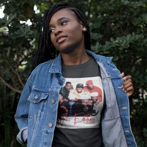 May include: A dark gray t-shirt with a printed image of the band New Edition. The image is from their 1990 album. The band members are all wearing hats and are smiling.