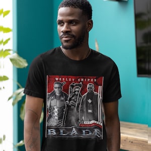 May include: Black t-shirt with a graphic of Wesley Snipes from the film Blade. The design includes images of the actor and the word "BLADE". The t-shirt has a crew neck and is a classic style.