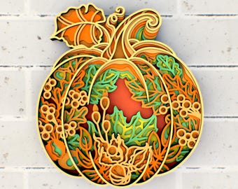Puede incluir: Una calabaza de madera en capas con intrincados recortes de hojas y enredaderas. La calabaza está pintada en tonos de naranja, verde y marrón.