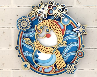 May include: A papercraft snowman ornament with a blue, white, and gold design. The snowman is wearing a red and gold scarf and a red hat. The ornament is surrounded by snowflakes and stars.