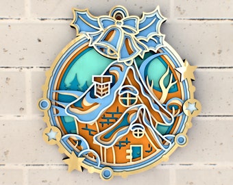 May include: A blue and gold paper ornament with a 3D design of a house with a chimney, a bow, and bells. The ornament has a blue and green background with stars and swirls.