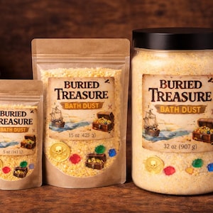May include: Three containers of "Buried Treasure" bath dust. The containers include a small pouch, a medium pouch, and a large jar. Each container has a label with a pirate ship, treasure chest, and the words "Buried Treasure Bath Dust".
