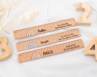 May include: Three wooden rulers with rainbow designs and the names Robin, Noah, and Amalia printed on them. Each ruler has a motivational quote in German. The rulers are accompanied by three wooden numbers: 2, 3, and 4.
