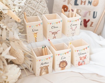May include: Six square wooden pencil holders featuring colorful bunting flags and illustrations of a giraffe, deer, rabbit, bear, lion, and fox. Each holder is personalized with the names Nina, Clara, Emma, Matteo, Lio, and Timon.
