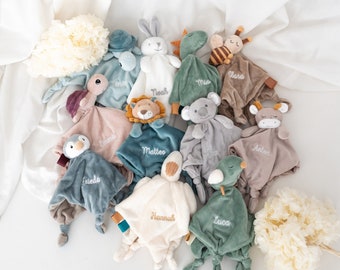May include: A collection of 12 plush toys with different animal designs, each with a personalised name embroidered on them. The toys are in various shades of green, brown, and white.