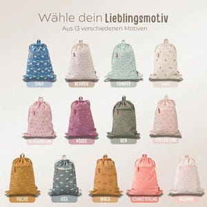 May include: Collection of drawstring backpacks in various colors and patterns, including dinosaurs, berries, and floral designs. Each bag has a drawstring closure and a small zippered pocket. Text at the top reads "W&auml;hle dein Lieblingsmotiv" and "Aus 13 verschiedenen Motiven."