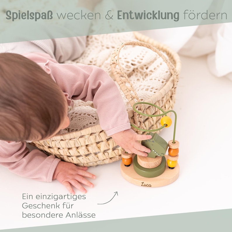 Peut inclure: Jouet en bois pour b&eacute;b&eacute; avec un alligator vert, des perles jaunes et une base en bois. Le jouet a un labyrinthe en fil de fer et est &eacute;tiquet&eacute; "Luca". L'image comprend &eacute;galement un panier en osier et du texte qui dit "Spielspa&szlig; wecken & Entwicklung f&ouml;rdern" et "Ein einzigartiges Geschenk f&uuml;r besondere Anl&auml;sse."