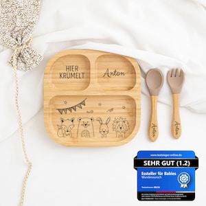 Może przedstawiać: Drewniany talerz z przegrodami z wygrawerowanym tekstem "Hier Krümelt" i "Anton". Talerz ma wzór z lisem, niedźwiedziem, królikiem i lwem z banerem nad nimi. Do talerza dołączona jest pasująca łyżka i widelec z wygrawerowanym imieniem "Anton".