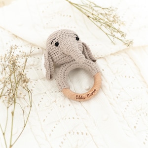 K&ouml;nnte beinhalten: Ein geh&auml;keltes Elefantenrassel mit einem Holzring. Der Ring ist mit dem Text "Edda-Marie" graviert.