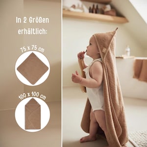 May include: A baby wearing a hooded brown towel, with the text "In 2 Sizes available: 75 x 75 cm" and "100 x 100 cm". The baby is holding a wooden brush. The towel is a light brown color.