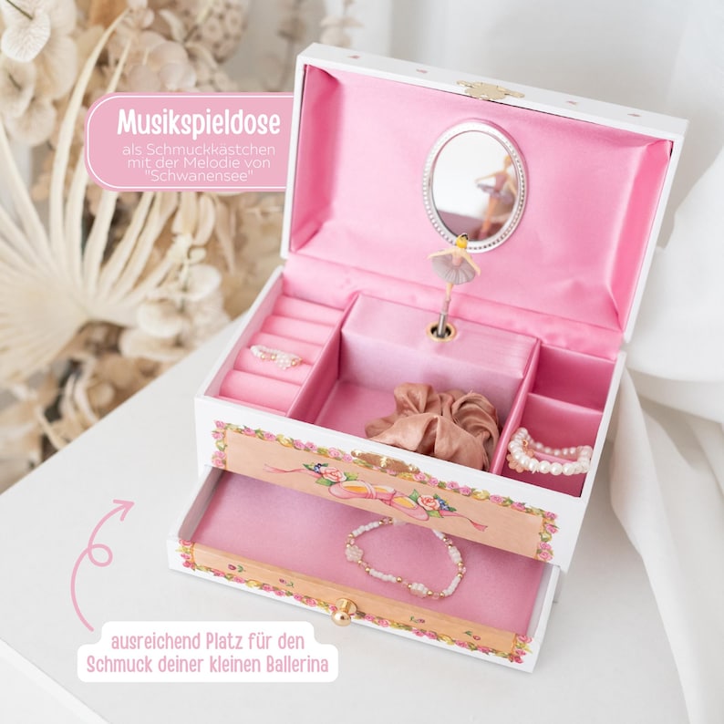 May include: White music box with a ballerina figurine and a mirror. The box has a drawer and compartments for jewelry. The text on the box reads "Musikspieldose als Schmuckk&auml;stchen mit der Melodie von "Schwanensee" ausreichend Platz f&uuml;r den Schmuck deiner kleinen Ballerina".