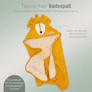May include: A yellow hooded baby towel with a lion face design. The towel has a white interior with small yellow spots. The hood features a lion's face with the name "Emilia" embroidered on it. The towel is designed for personalization.