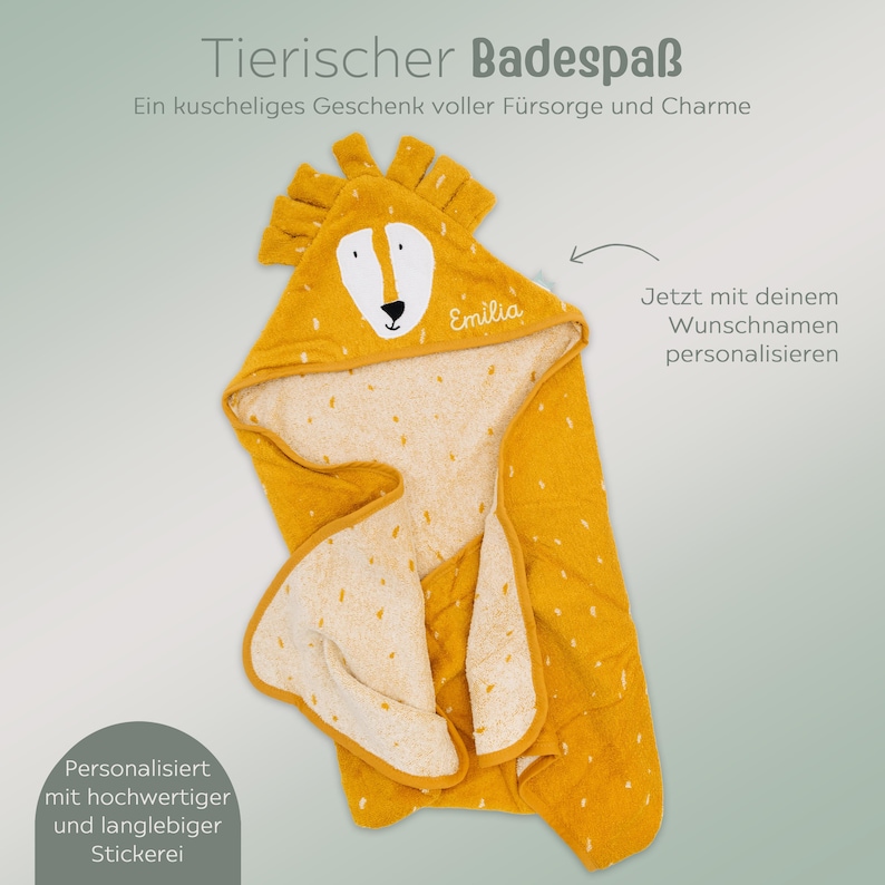 May include: A yellow hooded baby towel with a lion face design. The towel has a white interior with small yellow spots. The hood features a lion's face with the name "Emilia" embroidered on it. The towel is designed for personalization.