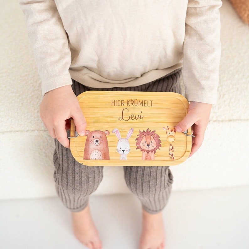 Puede incluir: Una bandeja de madera con una ilustraci&oacute;n de un oso, un conejo, un le&oacute;n y una jirafa. La bandeja tiene el texto "Hier kr&uuml;melt Levi" grabado.