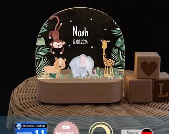 May include: A semi-circular acrylic night light with a wooden base, featuring a printed jungle scene with a monkey, lion, elephant, and giraffe. The text "Noah" and "17.08.2024" is printed in white. The light is dimmable and battery-operated.
