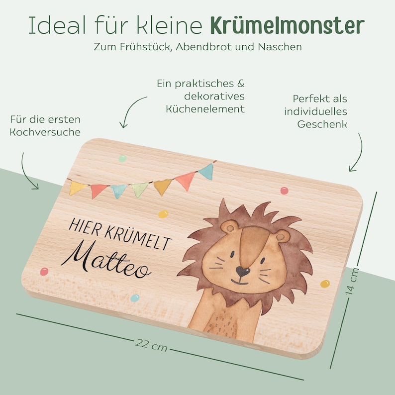 May include: A rectangular wooden cutting board measuring 22 cm by 14 cm. The board features a watercolor illustration of a lion, a colorful bunting banner, and the printed text "HIER KR&Uuml;MELT Matteo". The wood has a light, natural grain finish.