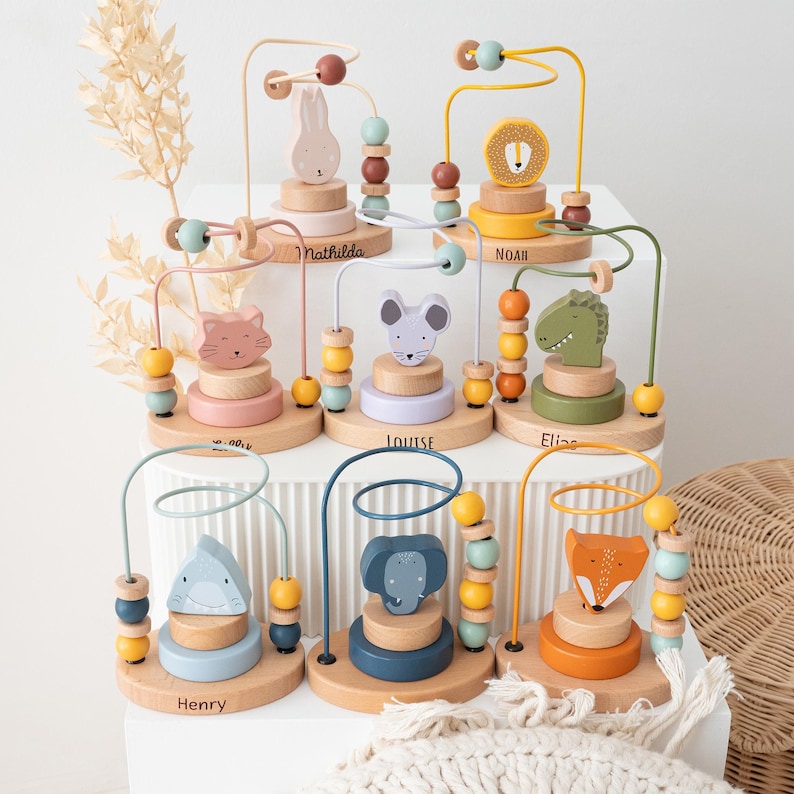 Peut inclure: Plusieurs jeux de labyrinthe de perles en bois pour enfants, chacun avec un animal diff&eacute;rent : lapin, lion, chat, souris, alligator, requin, &eacute;l&eacute;phant et renard. Chaque base porte un nom. Les jeux ont des perles aux couleurs pastel.