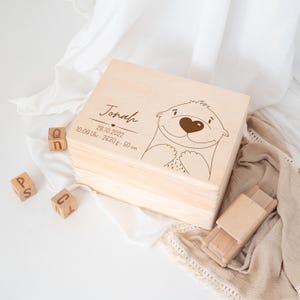 May include: A wooden keepsake box with a cute otter illustration and the name Jonah engraved on the lid. The box also includes the date 28.10.2022, time 10:09, weight 2630g, and length 50 cm.