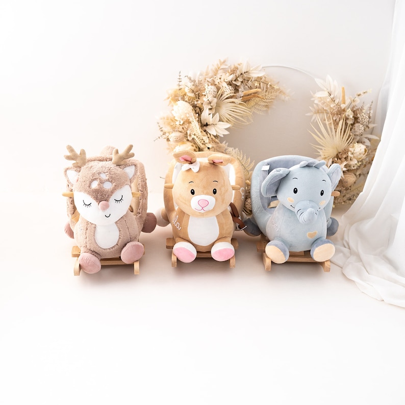 May include: Three plush rocking animals for children. A brown deer, a brown bunny, and a blue elephant. Each animal has a wooden base and a plush body.