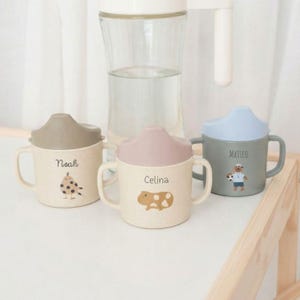 May include: A set of three ceramic mugs with a speckled, matte finish in cream, light grey, and dark grey. Each mug has a simple, minimalist design and a rounded handle.