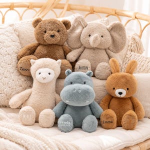 Può includere: Una collezione di cinque peluche che include un orso marrone con il nome Levin, un elefante beige con il nome Anton, un lama color crema con il nome Merle, un ippopotamo blu con il nome Frieda e un coniglio marrone con il nome Emma.
