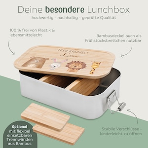 Puede incluir: Una fiambrera de metal blanco con tapa de bamb&uacute;. La tapa tiene una inscripci&oacute;n personalizada que dice "Hier kr&uuml;melt Levi". La fiambrera tiene un divisor extra&iacute;ble y un cierre seguro.