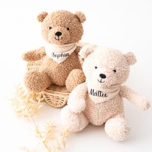 Könnte beinhalten: Zwei Plüschteddys, einer hellbraun und einer cremefarben, sitzen in einem Weidenkorb. Jeder Bär trägt ein cremefarbenes Halstuch mit einem in schwarzer Schrift gestickten Namen. Auf dem Halstuch des hellbraunen Bären steht "Sophia", auf dem des cremefarbenen Bären "Matteo".