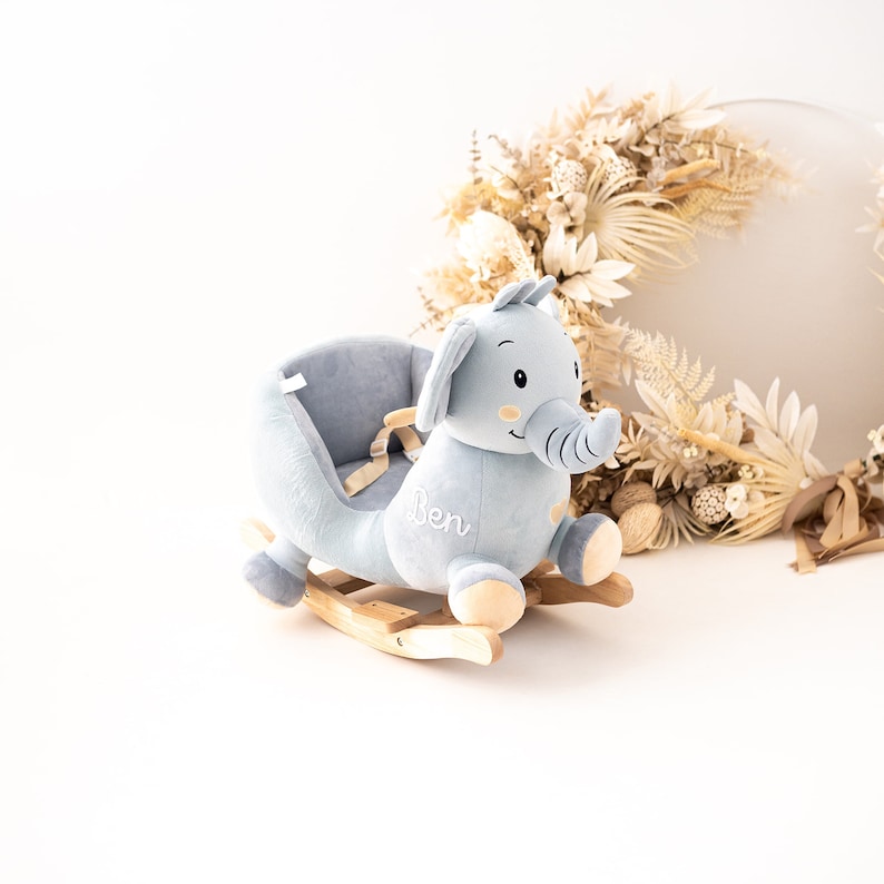 May include: A light blue plush rocking elephant with a wooden base. The elephant has a saddle and a name embroidered on the side: "Ben".