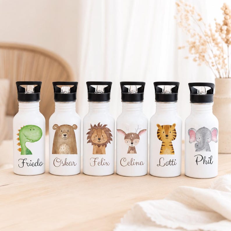 May include: Six white metal water bottles with black screw-top lids. Each bottle features a unique watercolor animal illustration and a name printed in black script: Friedo with a dinosaur, Oskar with a bear, Felix with a lion, Celina with a deer, Lotti with a tiger, and Phil with an elephant.