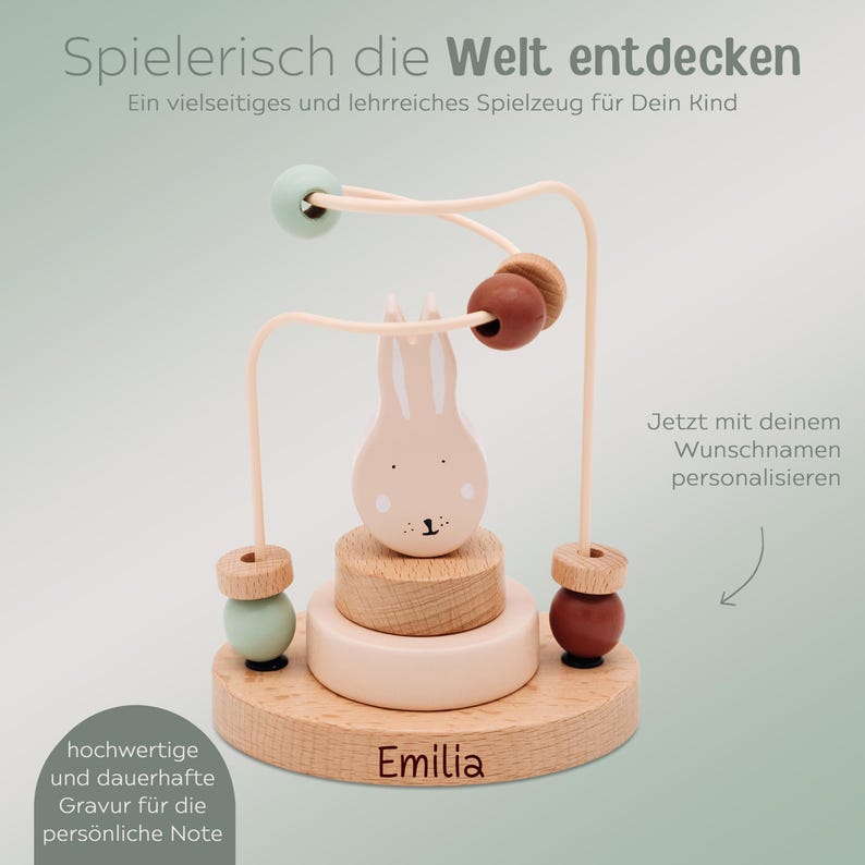Peut inclure: Jouet en bois pour b&eacute;b&eacute; avec un lapin et des perles color&eacute;es. Le jouet a une base en bois clair avec le nom "Emilia" grav&eacute;. Le texte "Spielerisch die Welt entdecken" est en haut.