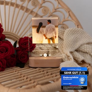 May include: A clear acrylic photo display with a wooden base, featuring a couple holding hands. The image is labeled "As Long as You Love Me" by Justin Bieber. The display includes a play/pause button and a progress bar. The base is rectangular and made of light-coloured wood.