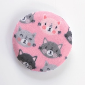 May include: Pink round fabric with a repeating pattern of gray and pink cartoon cats. The cats have black eyes and whiskers.
