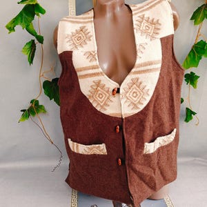 May include: A sleeveless vest featuring a deep brown main body and a cream-colored upper panel with a geometric diamond pattern. The vest includes three brown buttons down the center front and two front pockets with cream-colored patterned trim.