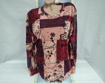 Puede incluir: Top de manga larga con patchwork en tonos burdeos, malva y rosa. El top presenta un cuello en V y está adornado con bordados florales y costuras decorativas. La tela parece ser un material transparente y ligero.