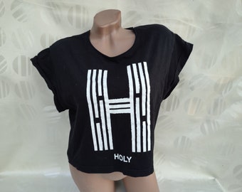 May include: Black cropped t-shirt with a white graphic of the letter "H" and the word "HOLY" printed below.