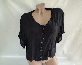May include: A black short-sleeved button-up top with a v-neckline. The top has a relaxed fit and is made of a lightweight fabric.