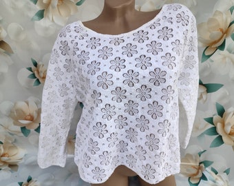May include: White crochet top with a floral pattern. The top has a scoop neck and 3/4 sleeves.