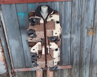 May include: A long brown, white, and black patterned vest with a zipper closure. The vest has a fuzzy texture and a high collar.