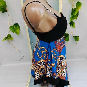 Puede incluir: Un top negro con una falda azul con un estampado dorado y blanco. La falda tiene un dise&ntilde;o de estampado de leopardo y un dobladillo negro. El top tiene tirantes de cadena.