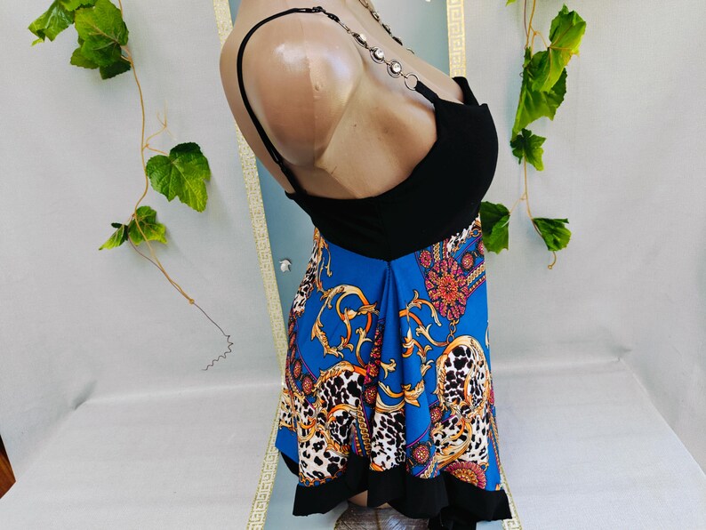 Puede incluir: Un top negro con una falda azul con un estampado dorado y blanco. La falda tiene un dise&ntilde;o de estampado de leopardo y un dobladillo negro. El top tiene tirantes de cadena.