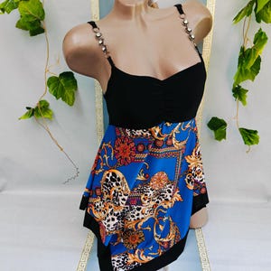 Puede incluir: Top negro con falda estampada en azul, naranja y dorado. El top tiene tirantes de pedrer&iacute;a y escote coraz&oacute;n. La falda presenta un dise&ntilde;o barroco con detalles de estampado de leopardo. La prenda se exhibe en un maniqu&iacute;.