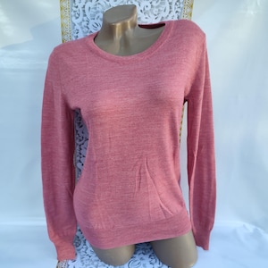Può includere: Un maglione rosa a maniche lunghe con collo rotondo.