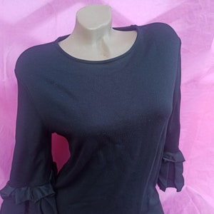 May include: A black long-sleeved shirt with ruffled sleeves. The shirt is made of a soft, stretchy fabric.